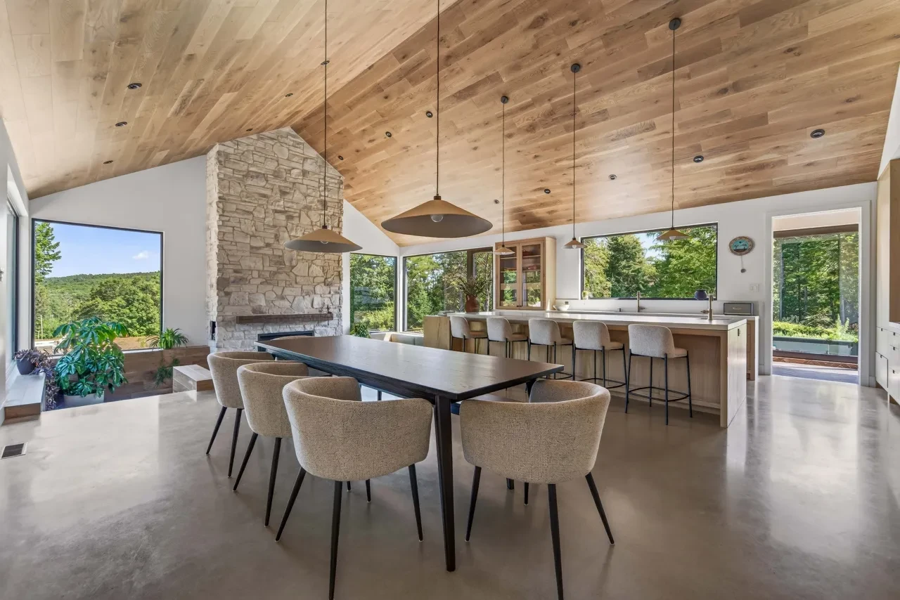 Salle à manger ouverte avec plafond en chêne et foyer en pierre
