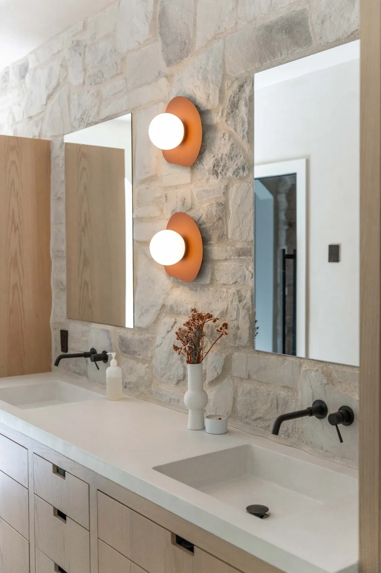 Salle de bain double vanité avec mur en pierre et appliques terracotta
